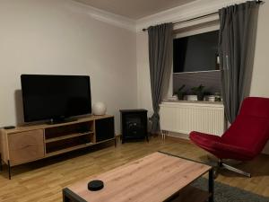a living room with a flat screen tv and a red chair at Ferienwohnung Anne in Großheide