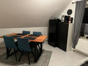 a dining room table with blue chairs and a black refrigerator at Ferienwohnung Anne in Großheide +7 photos