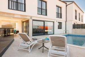 a patio with two chairs and a table and a pool at Villa SUNSET I with private pool and beautiful sea view in Vrbnik