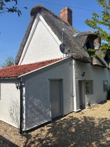 Cette petite maison blanche est dotée d'un toit de chaume. dans l'établissement Countryside Cottage in Bulmer- Sleeps 6 7, à Sudbury