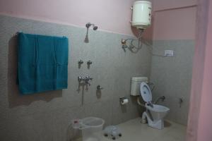 een badkamer met een toilet en een blauwe handdoek bij Tirthan Living Green Home Stays in Banjār