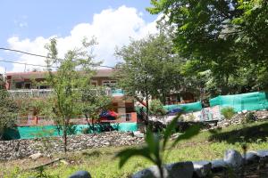 een gebouw met een zwembad en bomen bij Tirthan Living Green Home Stays in Banjār