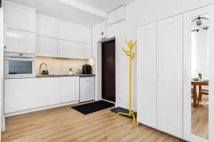 een keuken met witte kasten en een gele paal bij Piwna Apartament in Gdańsk +15 foto's