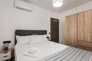 a bedroom with a white bed with two towels on it at M&A Boutique House in Zakynthos