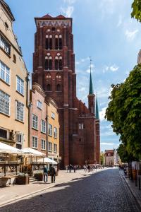 een groot bakstenen gebouw met een klokkentoren op een straat bij Piwna Apartament in Gdańsk