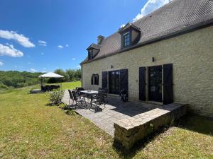 a patio with a table and chairs next to a building at DomaineRossignol Acacia in Gourdon-en-quercy