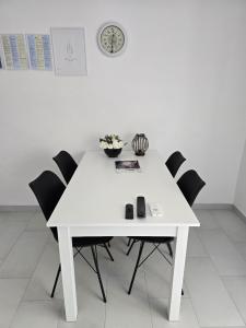 a white table with black chairs and a clock on the wall at Apartment Benda in Pag