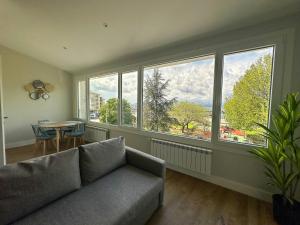 ein Wohnzimmer mit einer Couch und einem Tisch und Fenstern in der Unterkunft Apartamentos Marina Mar Vilagarcía 3000 in Villajuán