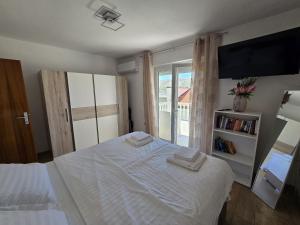 a bedroom with a white bed and a television at Apartment Benda in Pag +33 photos