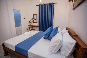 a bedroom with a bed with blue and white pillows at Mishu House in Ahangama