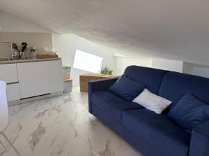 a living room with a blue couch and a kitchen at Golfo Ameno Apartment in Portovenere +6 photos