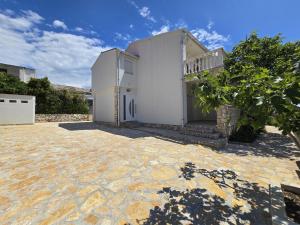 a white house with a stone patio in front of it at Apartment Benda in Pag