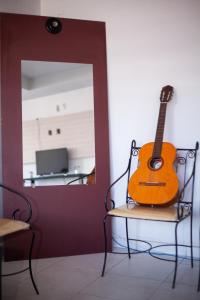 a guitar sitting on a chair in front of a mirror at Hotel Veneza in Garanhuns