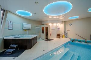 a large swimming pool with a large tub in a bathroom at Hotel Pušyno Namai in Tirkšliai