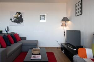 Una sala de estar con un sofá y un televisor. en L'Alto - Bel appartement lumineux -Vue panoramique, en Gare des Brotteaux