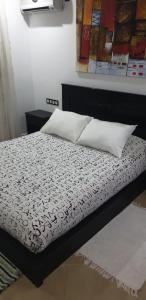 a bed with a black and white comforter and pillows at SALICORNE 1 marina saidia appt in Saïdia +41 photos