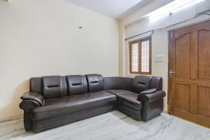a leather couch in a room with a wooden door at Via Prestige Castle - Nr HITEX Exhibition Center Hitech City in Hyderabad