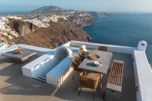 Un balcón con mesa y sillas y el mar. en Pura Vida Villa, en Imerovigli