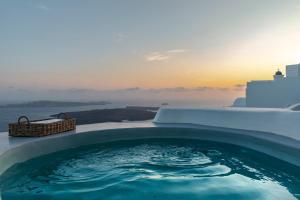 bañera de hidromasaje con puesta de sol en el fondo en Pura Vida Villa, en Imerovigli