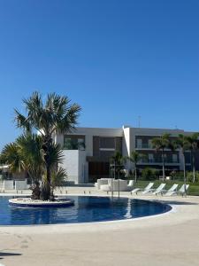 a pool with chairs and a palm tree in front of a building at Eleven Views in Chipiona