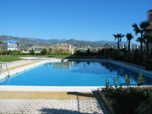 a large blue swimming pool with a city in the background at Terrasol Azucarera Atico H in Torre del Mar
