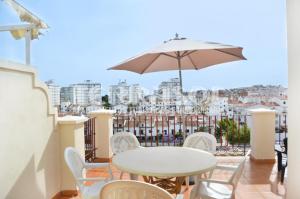 a table and chairs on a balcony with an umbrella at Terrasol Azucarera Atico H in Torre del Mar