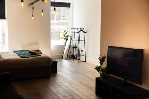 a living room with a bed and a flat screen tv at Chic Brighton Studio in Brighton & Hove