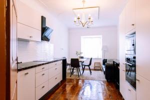 a kitchen with white cabinets and a dining room at Cozy flat in Center in Maribor