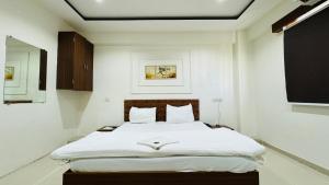 a bedroom with a large bed with white sheets at Hotel Palladium in Surat