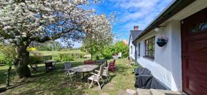 a patio with a table and chairs and a tree at Fridfullt sommarhus mitt på Österlen nära Simrishamn, Tomelilla och Ystad in Gärsnäs
