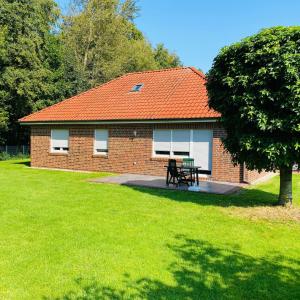 una casa de ladrillo con techo naranja y mesa de picnic en Bungalow Waldglück, en Hage
