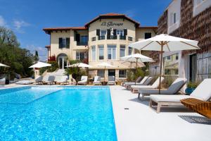 a pool with chairs and umbrellas next to a building at La Garoupe-Gardiole in Antibes