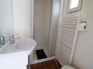 a small bathroom with a sink and a shower at Chalet in Friesland near Wadden Sea in Tzummarum +29 photos