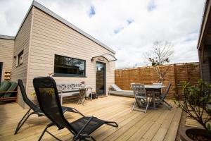 a patio with chairs and a table on a wooden deck at Le petit Préau 10 min plages in Coudeville