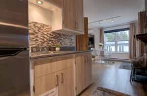 una cucina con mobili in legno e un muro di mattoni di Detente Nature bord de Lac #2 Spa Sauna & Foyer a Sainte Brigitte de Laval Altre 44 foto