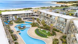 an aerial view of a resort with a pool and the ocean at Beachfront Getaway in Torquay