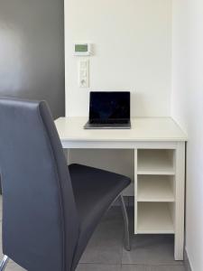einen Laptop auf einem weißen Schreibtisch mit Stuhl in der Unterkunft Parking privé - Accès PMR - Terrasse vue châteaux - 2 lits in Châtenois