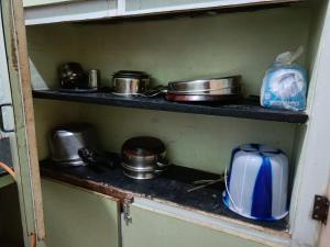 a shelf with pots and pans and a microwave at Adb's Srirangam Homes at Gandhi Road in Tiruchirappalli
