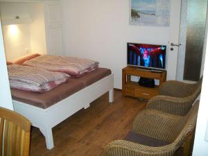 1 Schlafzimmer mit einem Bett, einem TV und 2 Stühlen in der Unterkunft Strandappartement in Westerland + 2 Fotos