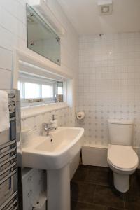 un bagno bianco con lavandino e WC di 7 Coastguards Cottages - Aldeburgh Coastal Cottages ad Aldeburgh Altre 14 foto