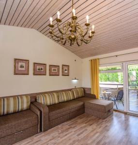 a living room with a couch and a chandelier at Apartamentai Trys pušys in Šventoji