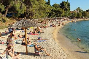 a crowd of people on a beach with an umbrella at Apartmani Sofija in Bibinje