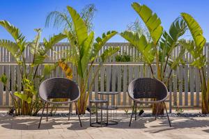 two chairs and two tables and a fence with plants at Arfna Villas in Afantou +48 photos