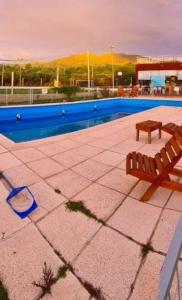 Dos bancos sentados junto a una piscina. en Complejo Buena Vista Capilla del Monte, en Capilla del Monte