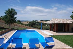 a swimming pool with chairs and a house at B&B Profumo delle Marche in Montefano