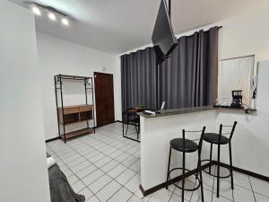 a kitchen with a counter and stools in a room at Edifício Herminio Muzzi Filho in Timóteo
