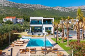 a villa with a swimming pool and mountains in the background at Seaview Villa Stanka with Pool and attached Jacuzzi in Kaštela