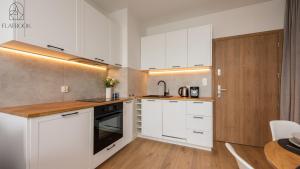 una cucina bianca con armadi bianchi e tavolo di Flatbook Apartamenty - Sztutowo Perła Mierzei a Sztutowo