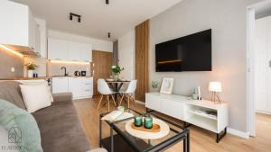 un soggiorno con divano e TV e una cucina di Flatbook Apartamenty - Sztutowo Perła Mierzei a Sztutowo
