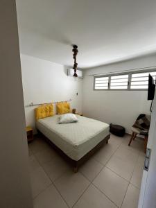 Un dormitorio con una cama con almohadas amarillas. en appartement T2 Soléia Zen, en Le Gosier